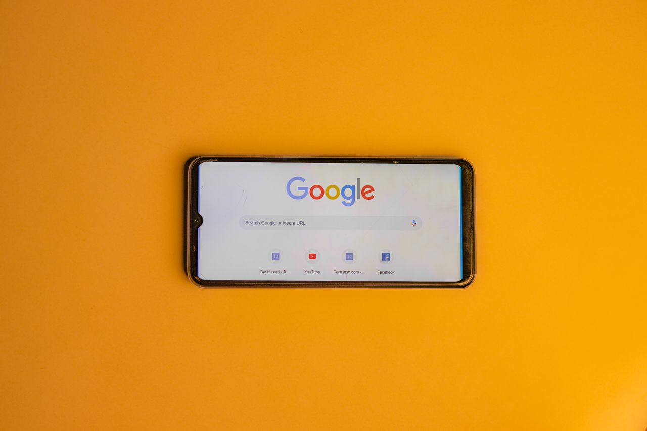 services-01 Smartphone displaying Google search page on a vibrant yellow background.