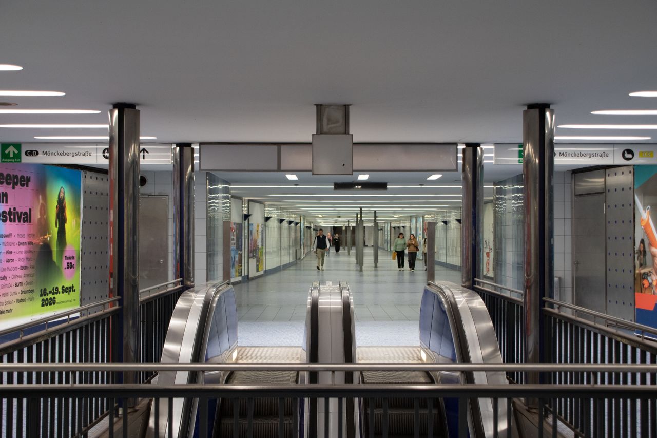Modern escalator leading to a busy walkway in Hamburg underground station.